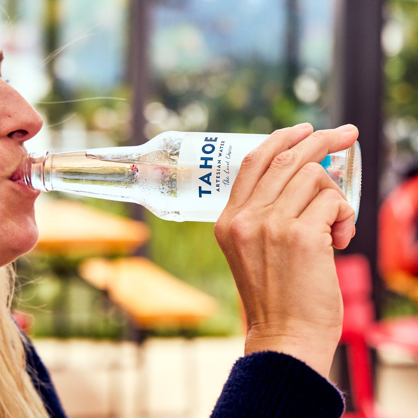 
                  
                    Person drinking from Tahoe artesian water bottle in an outdoor setting.
                  
                