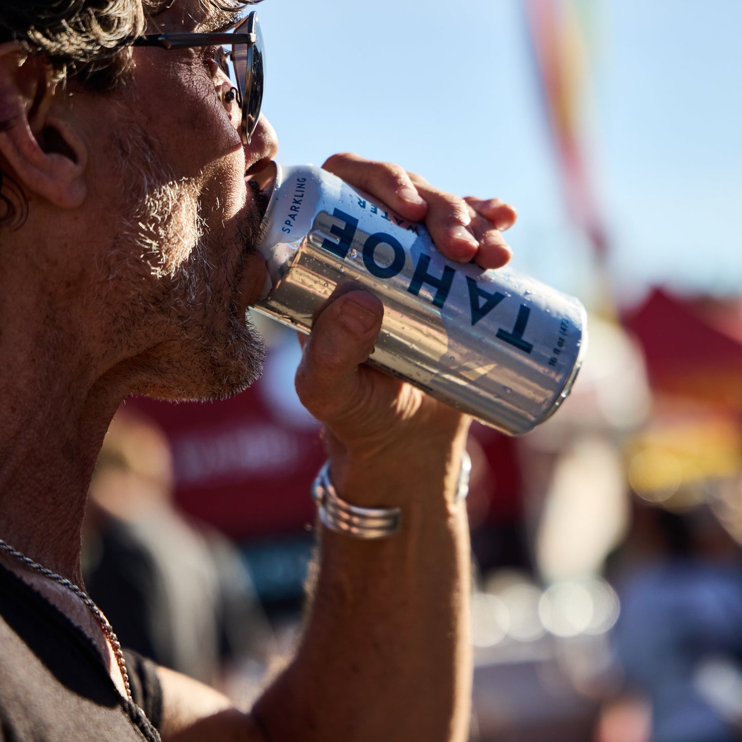 Person drinking from a Tahoe water can with a blurred outdoor background