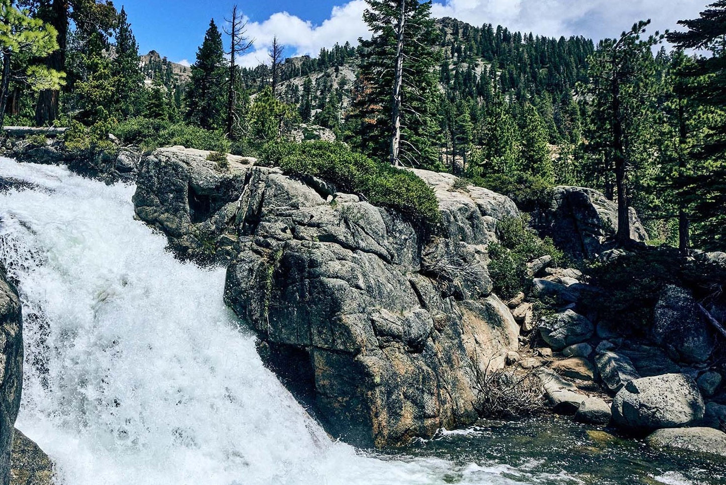Waterfall cascading over rocks with trees and mountains in the background